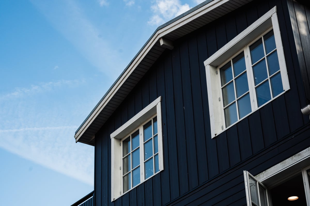 A residential exterior finished with deep blue siding and crisp white trim and windows